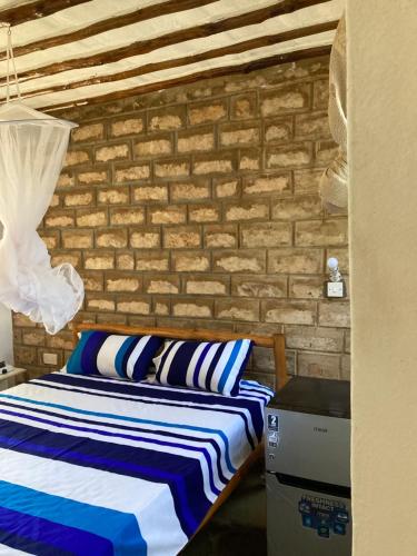 a bedroom with a bed and a brick wall at Petcat Cottage in Diani Beach