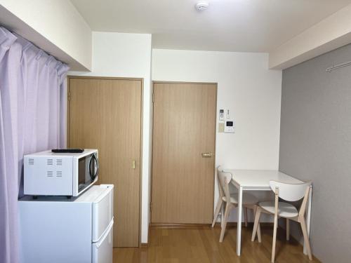 a small kitchen with a table and a microwave at ホテル駅前汐舎 in Nagasaki