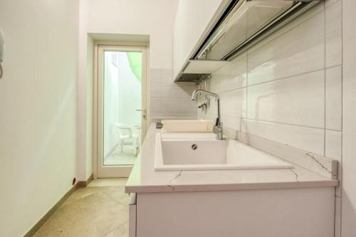 a white bathroom with a sink and a window at mono volta by salentolimit in Nardò