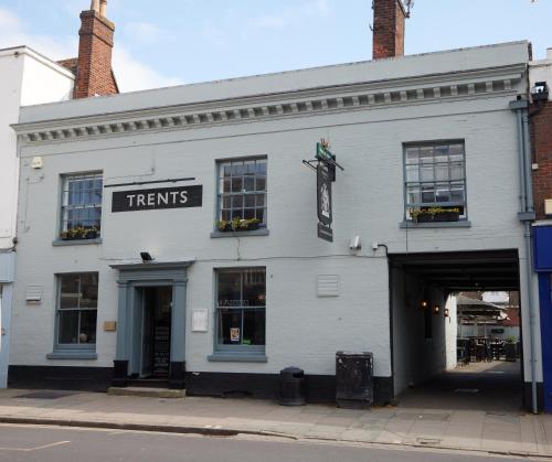 a white building with a sign that reads treats at Trents by Greene King Inns in Chichester