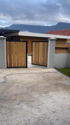 a house with two wooden garage doors on it at Le repaire de la mare in Salazie
