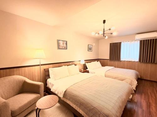 a hotel room with two beds and a chair at NIKYO Nishi 9 Private Villa OSAKA in Osaka
