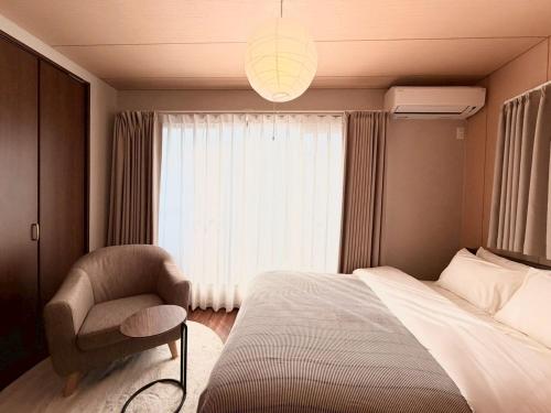 a bedroom with a bed and a chair and a window at NIKYO Nishi 9 Private Villa OSAKA in Osaka