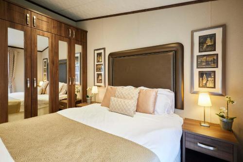 a bedroom with a large white bed and a mirror at Sutton Lodge with Hot Tub in York