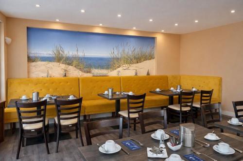 a restaurant with tables and chairs and a large painting on the wall at Hotel zur Traube in Kühlungsborn