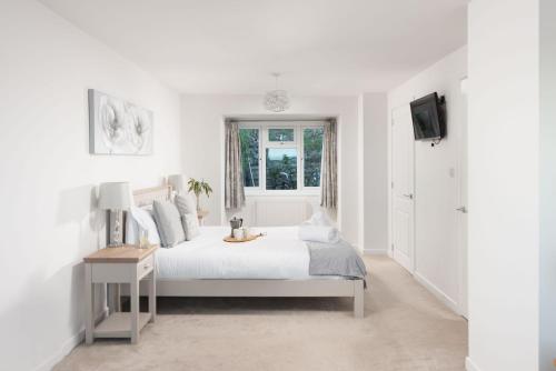 a white bedroom with a bed and a window at Little Chy an Mor in Coverack