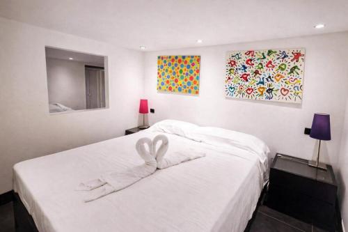 a bedroom with a white bed with a heart towel on it at Hotiday Rapallo Old Town in Rapallo