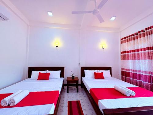 two beds in a room with red and white at Shan Villa Dambulla in Dambulla
