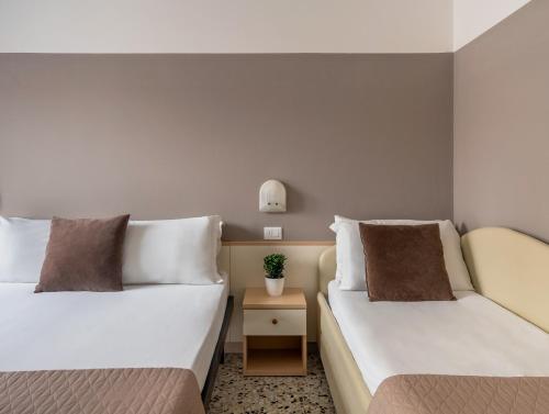 a bedroom with two beds and a table with a plant at Vibe Hotel in Cattolica