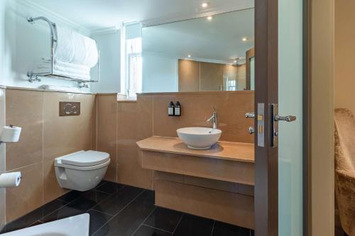 a bathroom with a sink and a toilet and a mirror at Radisson Blu Hotel, London Bloomsbury in London