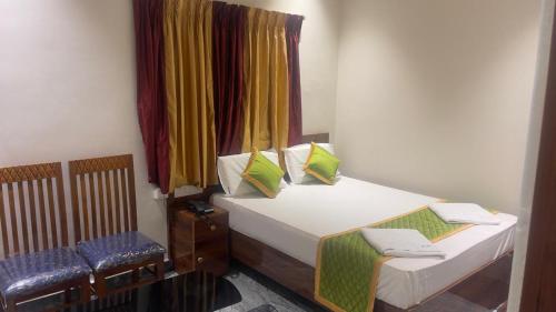 a small bedroom with a bed and two chairs at Swapnainn in Ongole