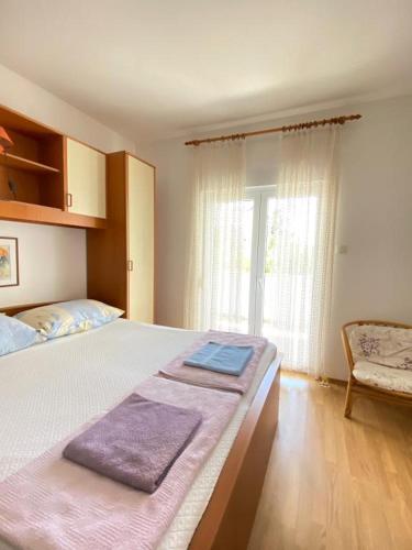 a bedroom with a large bed and a chair at Mia 4 in Crikvenica