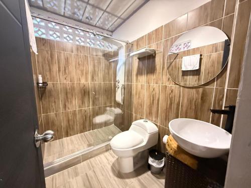 ein Badezimmer mit Toilette, Waschbecken und Spiegel in der Unterkunft Toba hotel in Ibagué