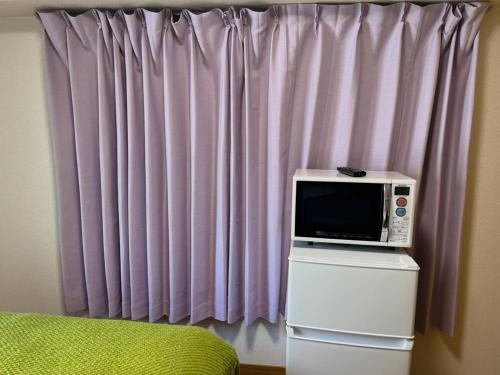 a microwave sitting on top of a dresser in front of a curtain at ホテル駅前汐舎 in Nagasaki