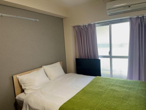 a bedroom with a bed and a large window at ホテル駅前汐舎 in Nagasaki