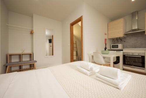 a white bedroom with a white bed and a kitchen at City Garden House by Hosty in Sacavém