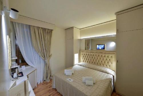 a bedroom with a bed and a television on the wall at Hotel Arcobaleno in Siena