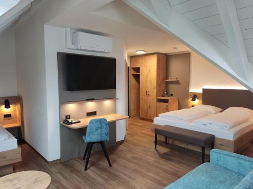 a bedroom with two beds and a desk with a tv at Hotel Waldhorn in Friedrichshafen