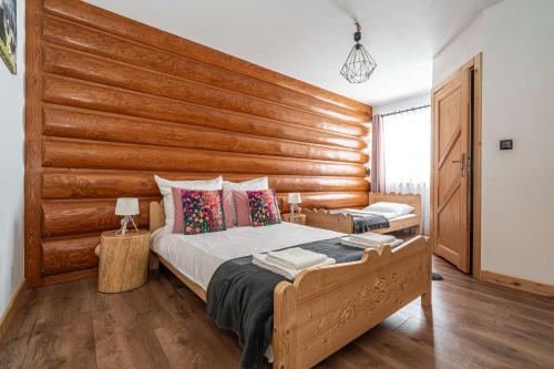 two beds in a bedroom with a wooden wall at Tarasówka u Zająca in Zakopane