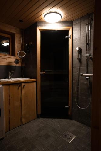 a bathroom with a door to a shower and a sink at Rahkis Lodge Saariselkä in Saariselka