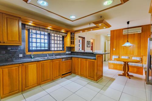 a large kitchen with wooden cabinets and a table at Resitour - Kamares Village in Paphos