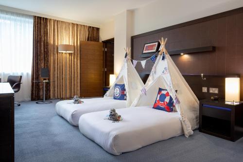 a hotel room with three beds with a canopy at Hilton London Canary Wharf in London