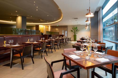 a restaurant with tables and chairs and a bar at Hilton London Canary Wharf in London