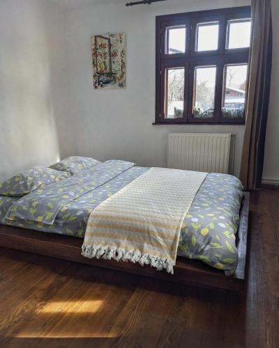 a bedroom with a bed with a blanket and a window at Thee&Thou Cottage in Breaza