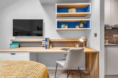 a bedroom with a desk with a chair and a television at Practical Studios In Lincoln with Free Grab&Go Breakfast in Lincoln