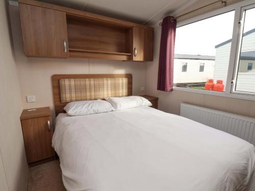 a bedroom with a white bed and a window at Caravan B14 Beechrise in Filey