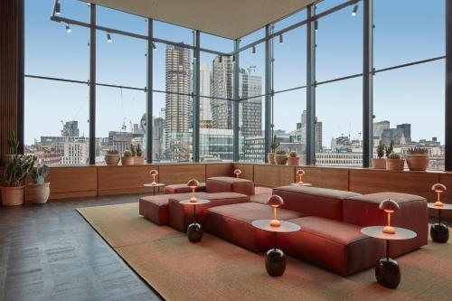 a large room with a red couch and large windows at One Hundred Shoreditch in London