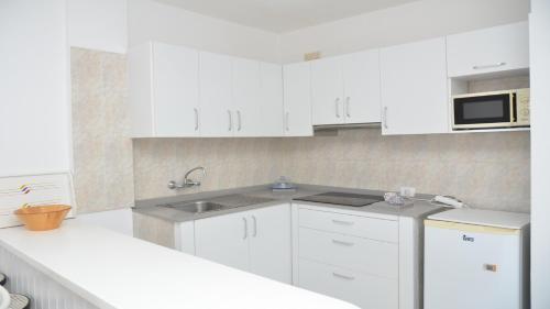a white kitchen with white cabinets and a sink at La Playa 2 A in La Laja