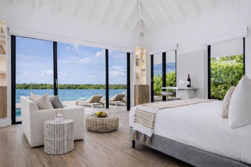 a bedroom with a large bed and large windows at Ambergris Cay - Private Island All-Inclusive in Big Ambergris Cay