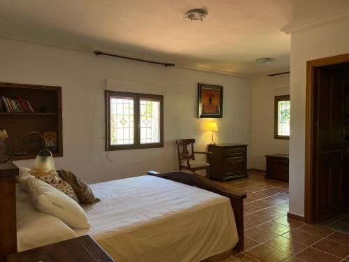a bedroom with a bed and a chair and windows at Casablanca in Candeleda