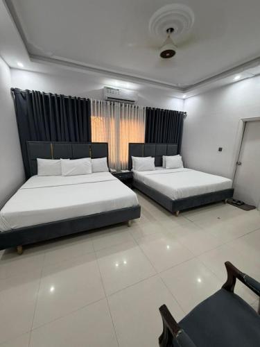 a bedroom with two beds and a window at Comfort Lodge in Karachi