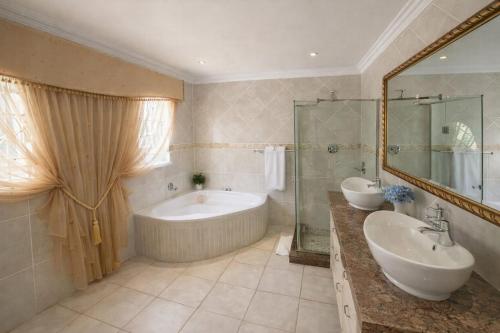 a bathroom with two sinks and a tub and a shower at La Barune Guest House in Tzaneen