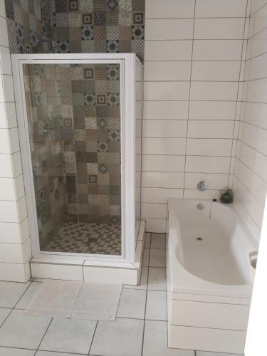 a white bathroom with a shower and a tub at Claypot Guesthouse in Northam