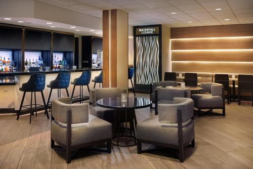 a lobby with a bar with chairs and tables at Sheraton West Des Moines in West Des Moines