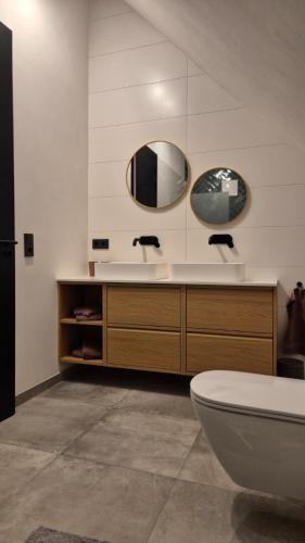 a bathroom with a sink and a toilet and two mirrors at Haus am FELS, Alpenaster in Hermagor