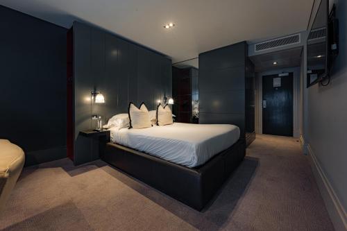 a bedroom with a large bed with white sheets and pillows at Dakota Eurocentral in Motherwell