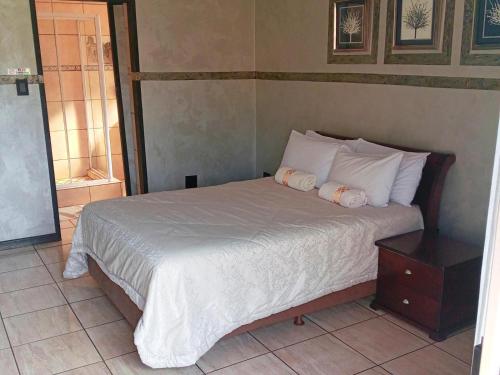 a bed with white sheets and pillows in a bedroom at Petra Lodge in Edenvale