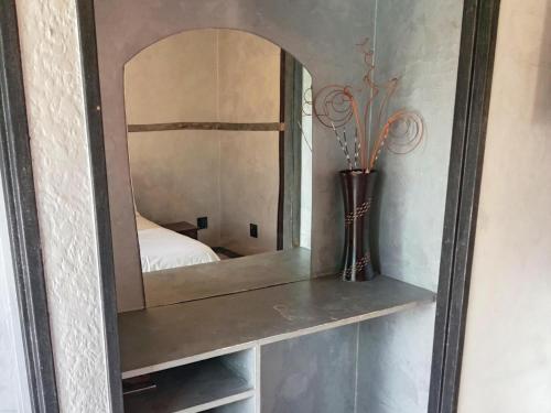 a mirror on a shelf with a vase on it at Petra Lodge in Edenvale