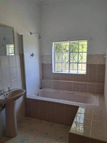 a bathroom with a tub and a sink and a window at Eenvoud in Rosendal