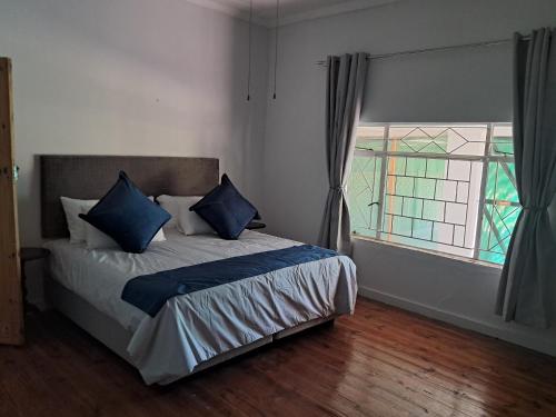 a bedroom with a bed with blue pillows and a window at Eenvoud in Rosendal