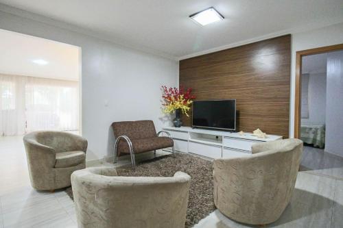 a living room with two chairs and a television at Casa com Piscina e Churrasqueira em Taguatinga in Taguatinga