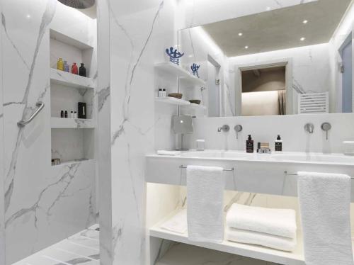 a white bathroom with a sink and a mirror at Semeli Estate Suites in Koútsion