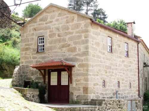 une vieille maison en pierre avec une porte rouge dans l'établissement Casa Do Pomar, à Parada