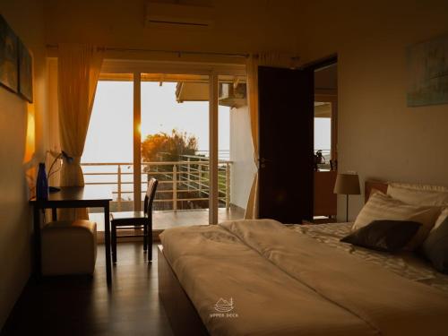a bedroom with a bed and a table and a balcony at The Upper Deck in Pīrmed