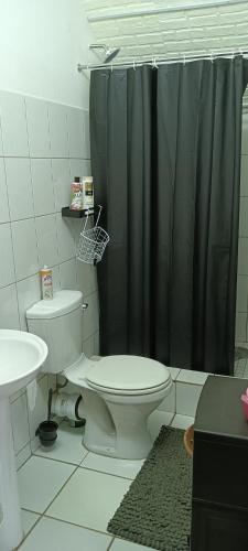 a bathroom with a toilet and a black shower curtain at Meltz Inn in Klerksdorp