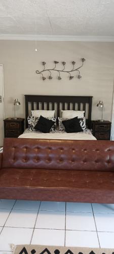 a large bed with a leather couch in a bedroom at Meltz Inn in Klerksdorp